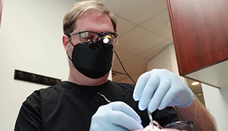 Doctor Bell wearing dental binoculars while treating a patient