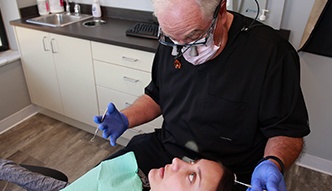 Doctor Walton wearing dental binoculars while treating a patient