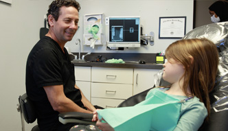 Doctor Tzagournis talking to young girl in dental chair
