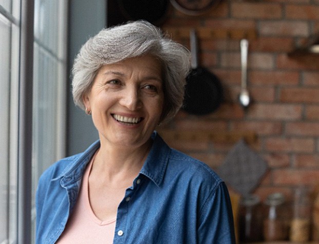 older woman smiling with a brick background