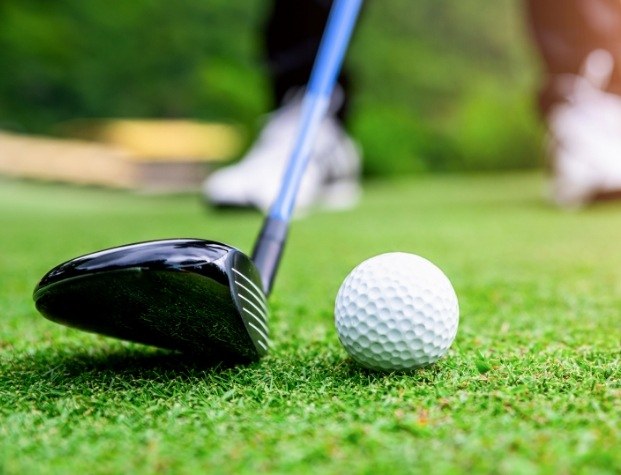 Golfer lining up their club with golf ball on ground