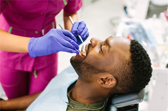 Dental assistant examining patient's teeth with dental tools