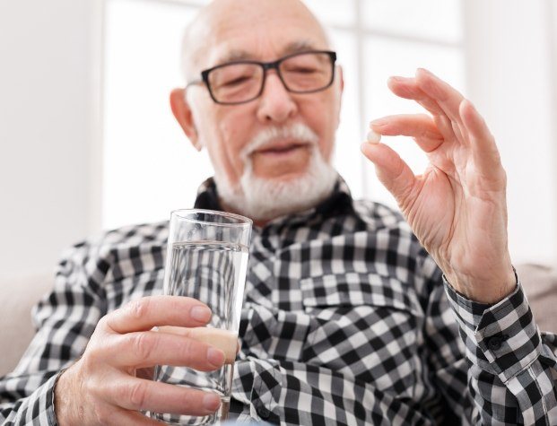 Man holding pill and glass of water