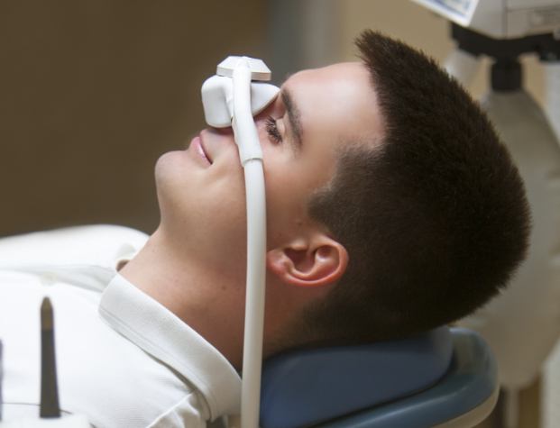 Man leaning back in dental chair with nitrous oxide mask over his nose