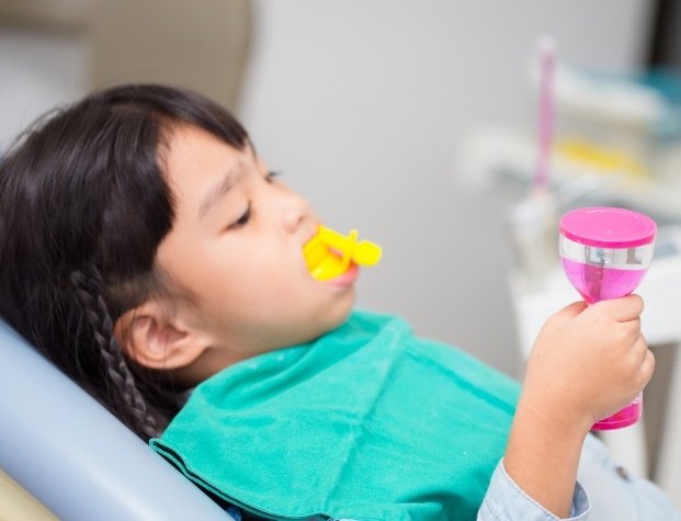 Young girl in dental chair with fluoride trays over her teeth