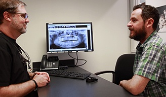 Doctor Bell sitting across desk from dental patient