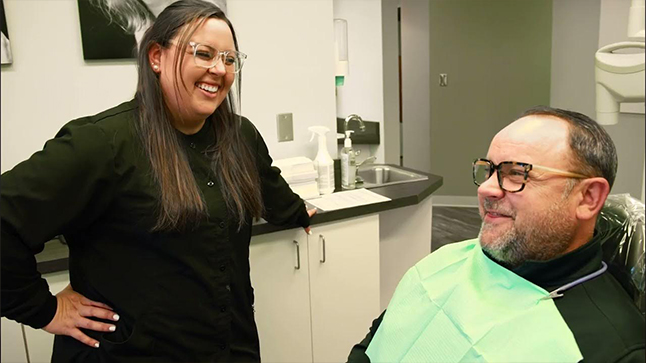Man in dental chair chatting with dental team member