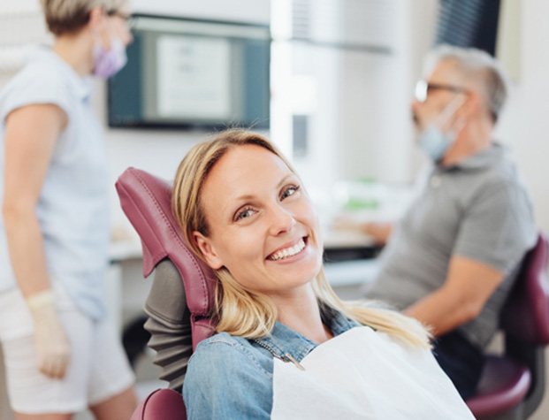 a patient smiling and holding a denture model